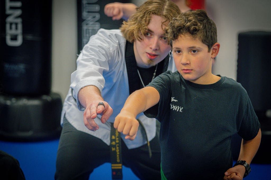 A Junior TaeKwonDo student practicing a punch with his instructor