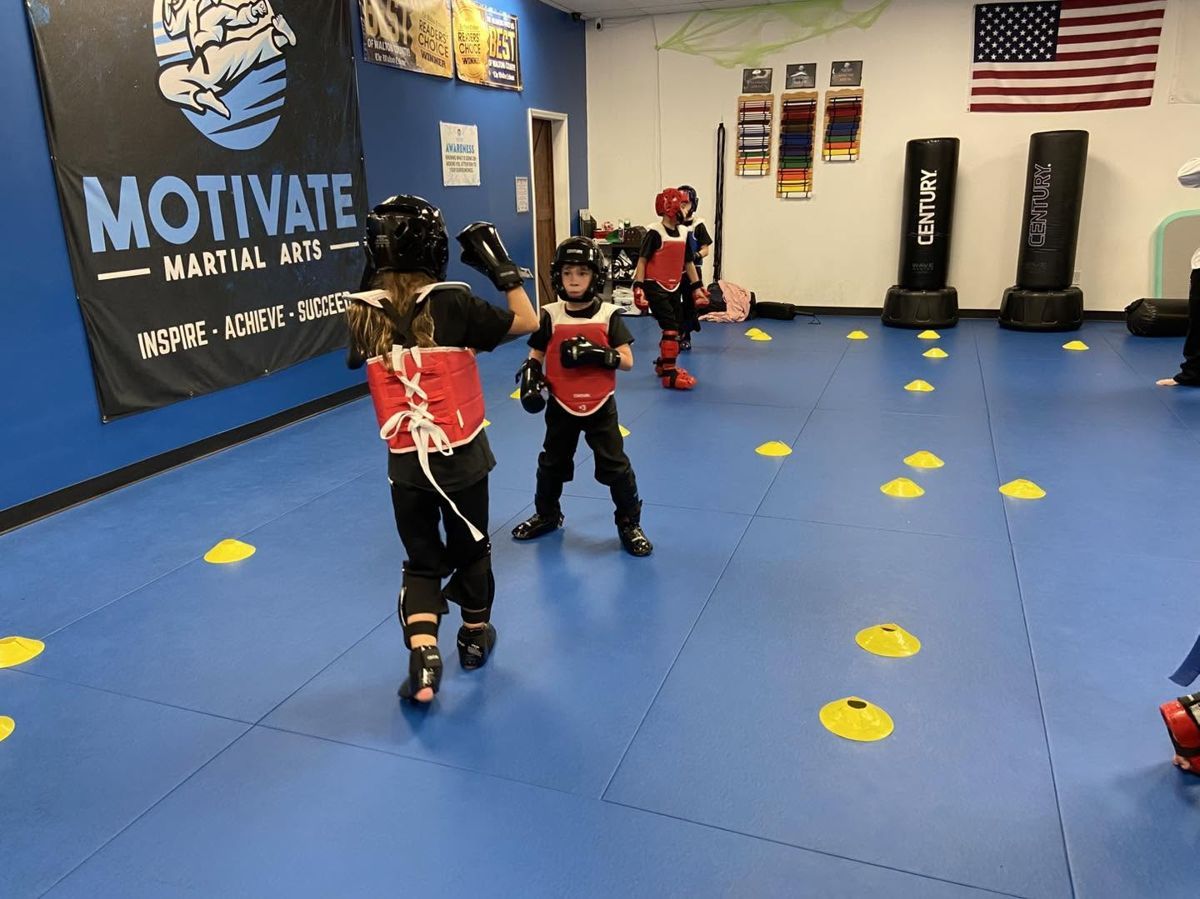 Junior students in sparring gear practicing on the blue mats