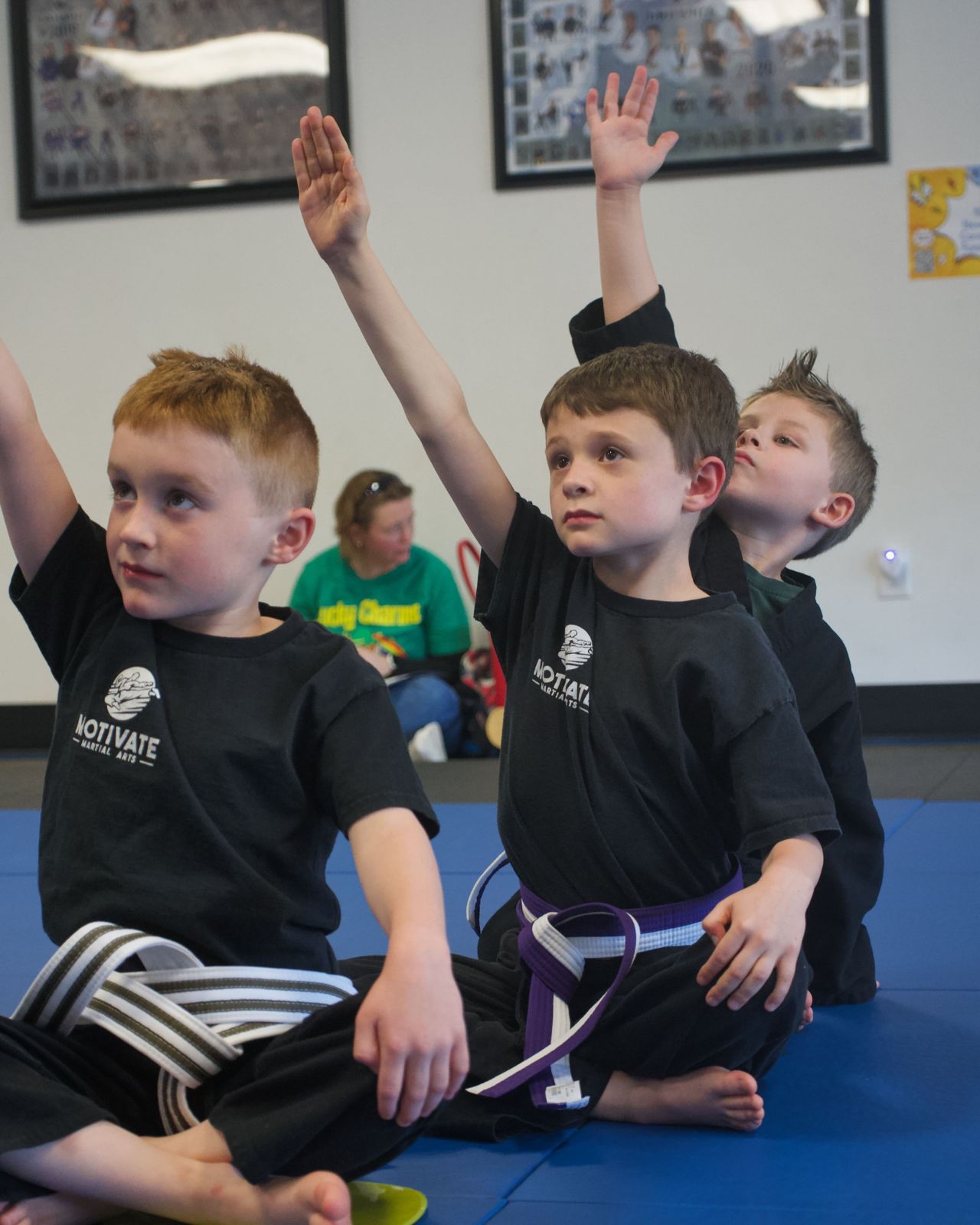 Young Motivate students raising their hands in class