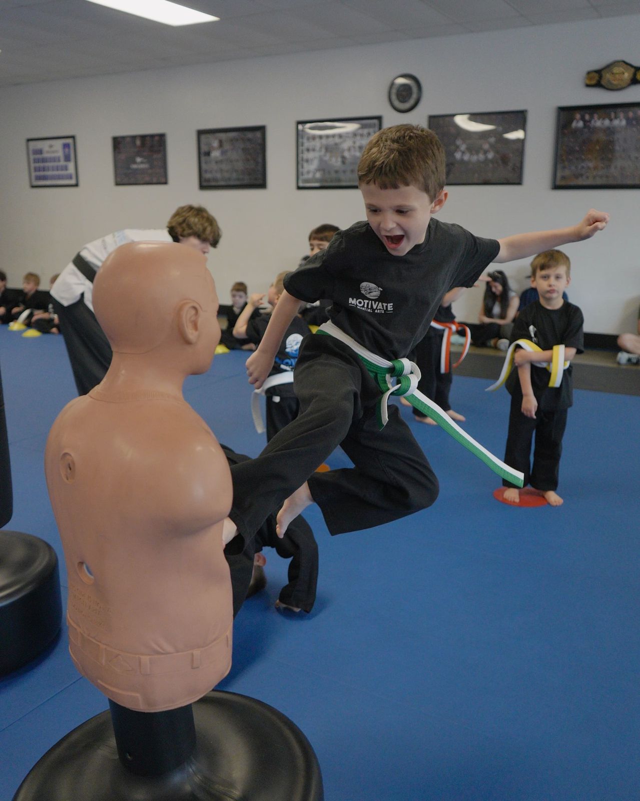 A young student kicking a target in class